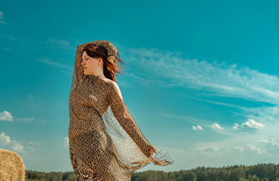 Rear view of woman standing on field against sky