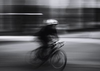 Blurred motion of person riding bicycle on road