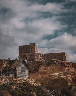 Low angle view of old buildings against cloudy sky