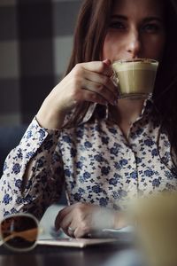 Midsection of woman drinking coffee