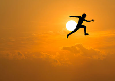 Silhouette man against orange sky