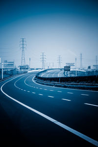 Vehicles on highway against clear blue sky