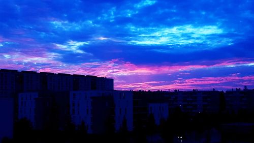 Silhouette buildings against blue sky at sunset