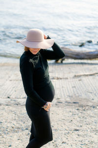 Portrait of a beautiful young pregnant woman in a black turtleneck and black tight skirt