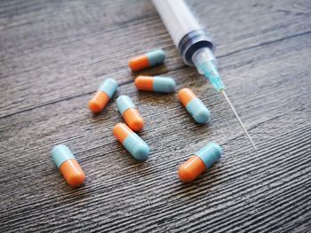 High angle view of syringe with medicines on table