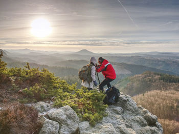 Silhouette man and girlfriend shooting sunset on the top mountain. photographer with eye at camera