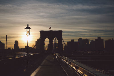 Bridge over river in city against cloudy sky