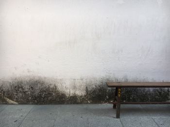 Empty bench against wall