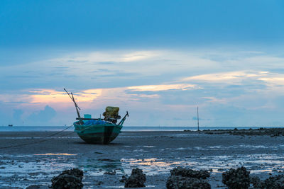 Fishing boat on sea against sky during sunset