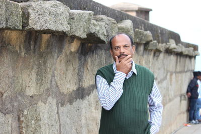 Portrait of senior man standing against wall