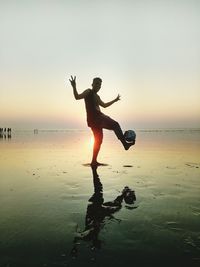 Portrait of man gesturing while playing soccer ball at beach