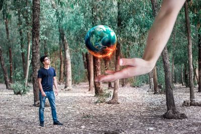 Full length of man holding tree trunk in forest