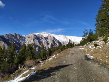 Road leading towards mountains against blue sky