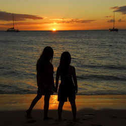 Rear view of women on beach during sunset