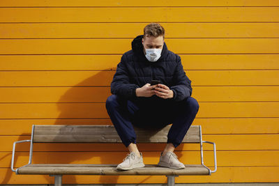Man wearing face mask sitting on bench