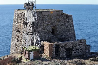 Lifeguard hut on rocks by sea against sky