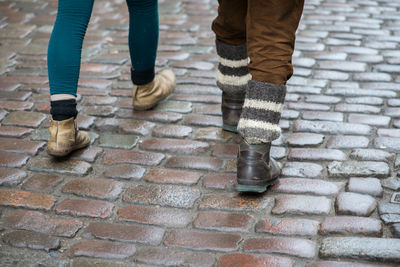 Low section of people walking on cobblestone