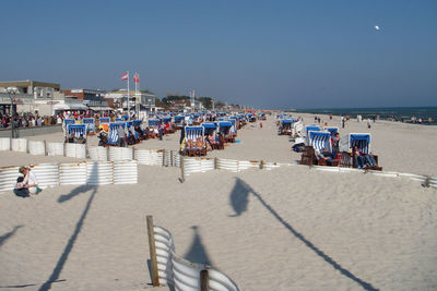 People relaxing on hooded chairs at sandy beach