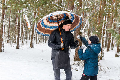 Rear view of man with umbrella standing in forest