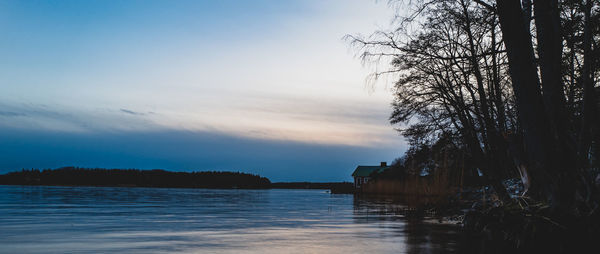 Silhouette trees by lake against sky during sunset