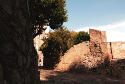 Stone wall by building against sky