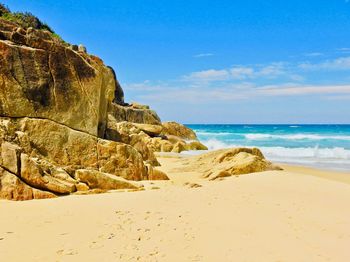 Rock formations on beach against sky