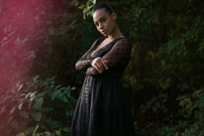 Portrait of young woman standing against plants