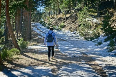 Rear view of woman walking on dirt road