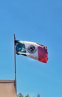 Low angle view of flag against clear blue sky