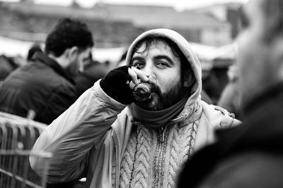 Portrait of man holding camera while standing outdoors