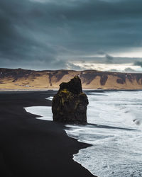 Rock formation on beach against sky