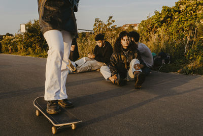 Rear view of people sitting on road along trees
