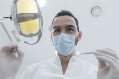 Low angle portrait of dentist holding medical equipment in hospital