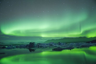 Scenic view of aurora borealis over lake against sky at night