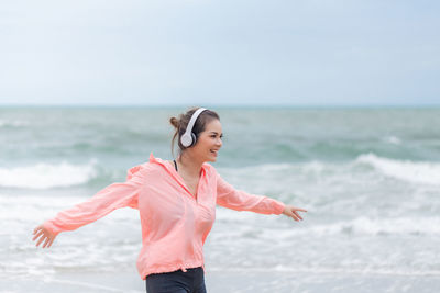 Woman standing at beach against sky