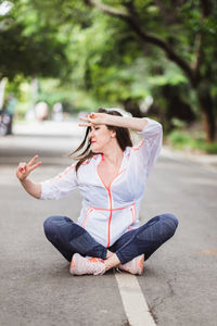 Portrait of young woman sitting on road