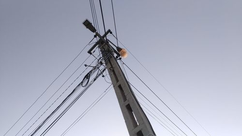 Low angle view of electricity pylon against clear sky