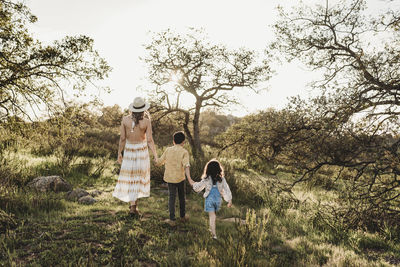 Back view of mother and children walking away in field