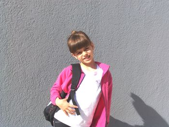 Portrait of a smiling young woman standing against wall
