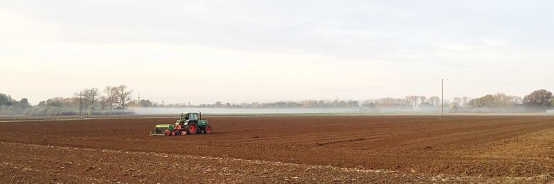 Tractor on agriculture field against sky