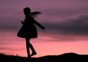 Silhouette of people standing on field at sunset