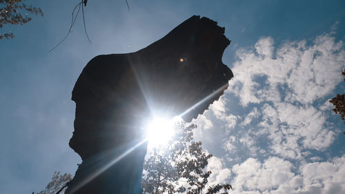 Low angle view of silhouette sculpture against sky on sunny day