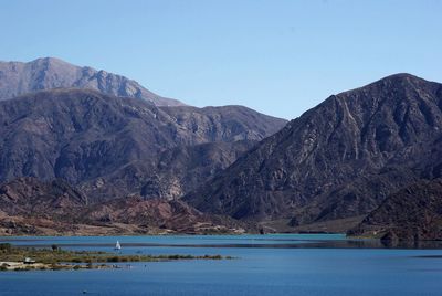 Scenic view of lake and mountains against clear blue sky