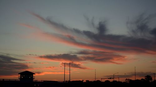 Silhouette buildings against dramatic sky during sunset