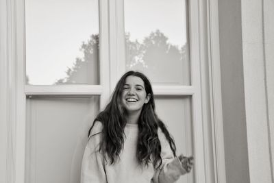 Portrait of smiling woman standing against closed door