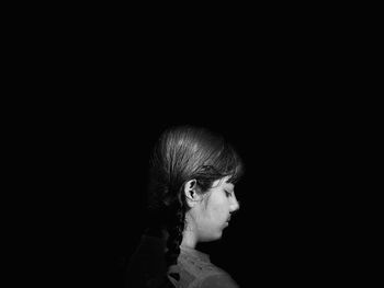 Close-up portrait of a woman against black background