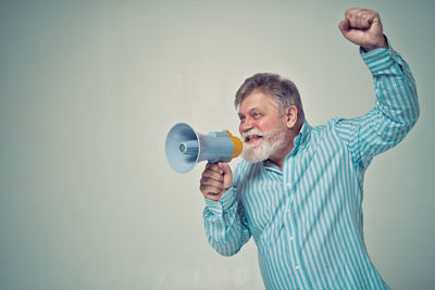 Full length of man holding camera over white background