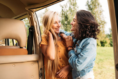 Female friends standing near car