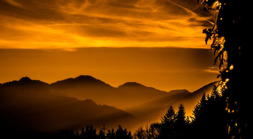 Scenic view of silhouette mountains against romantic sky at sunset