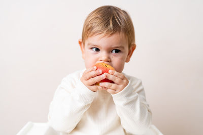 Portrait of cute boy eating against white background